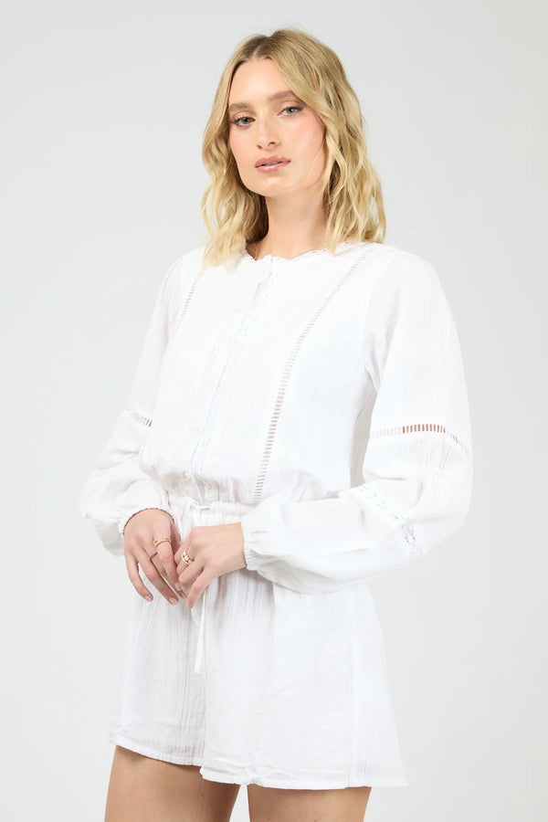 Model wearing the All About Eve Dusty Playsuit in white, featuring long sleeves, lace detailing, and a drawstring waist.