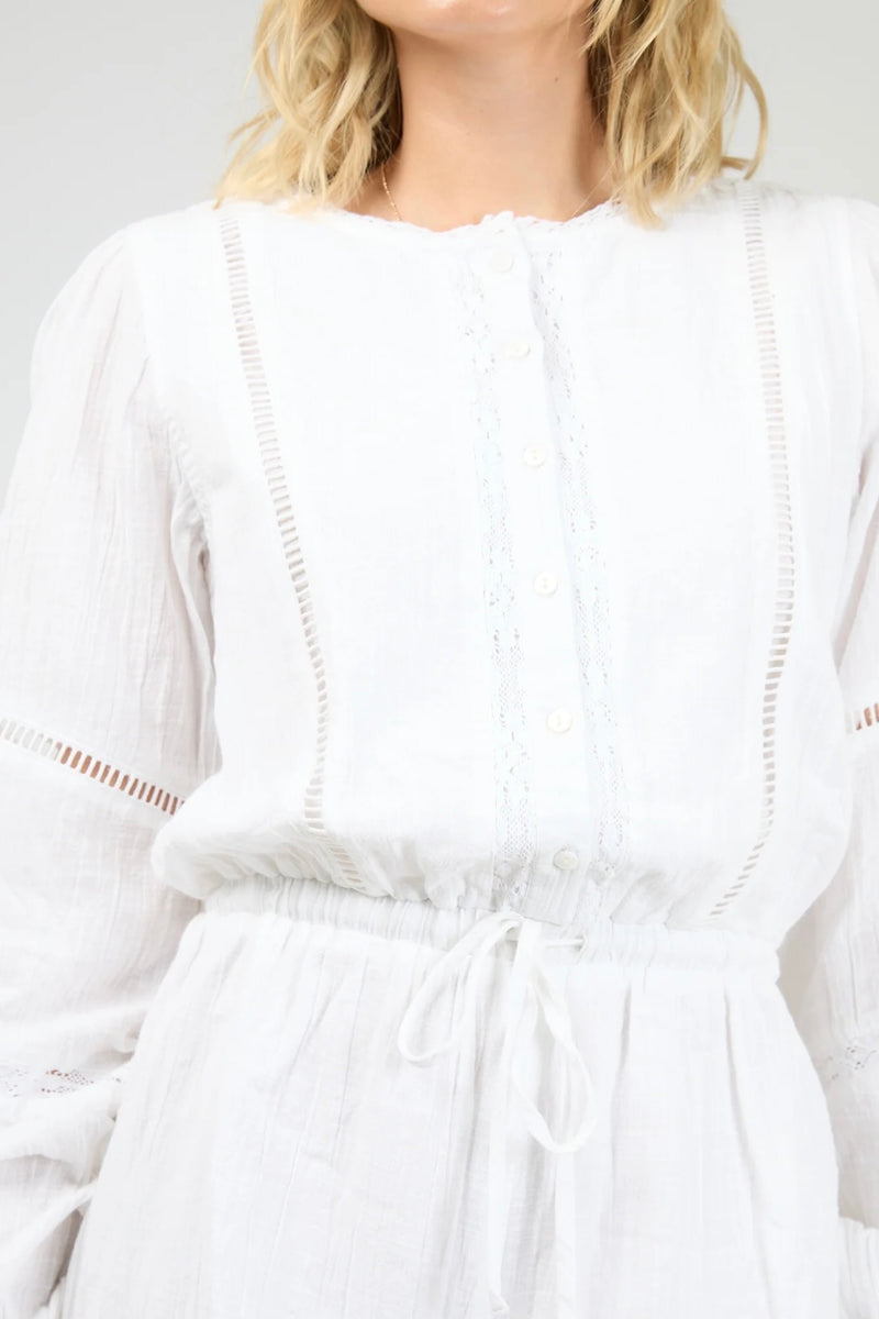 Model wearing the All About Eve Dusty Playsuit in white, featuring long sleeves, lace detailing, and a drawstring waist.