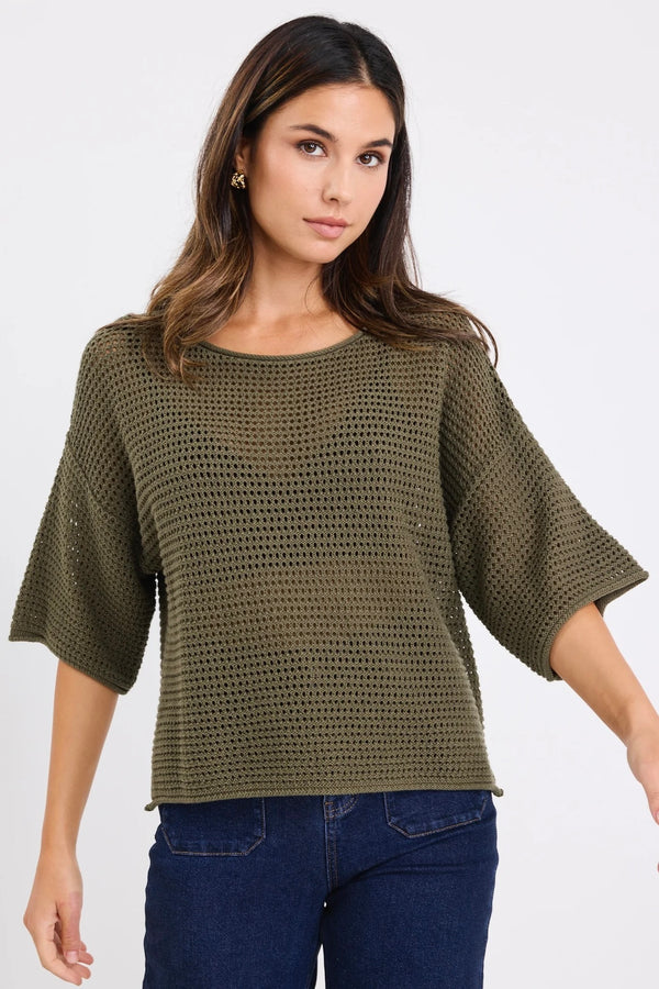 Woman wearing Re:Union The Label Sunrise Khaki SS Crochet Knit Top in crochet knit with short sleeves, relaxed fit, and round neckline, styled with denim jeans.