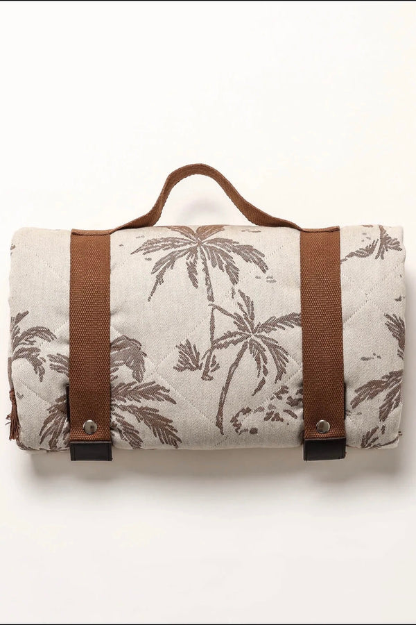 Rolled neutral palm print blanket with brown carry straps