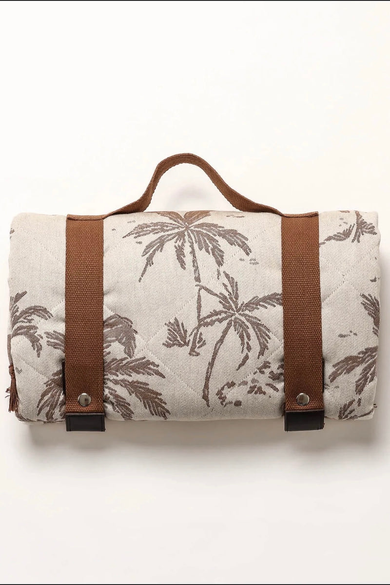 Rolled neutral palm print blanket with brown carry straps