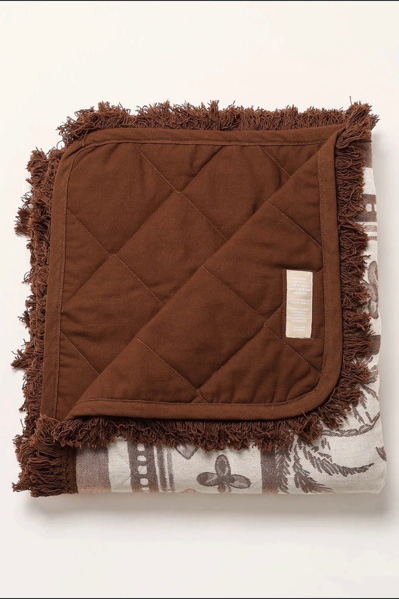 Rolled neutral palm print blanket with brown carry straps