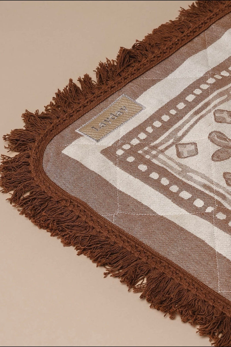 Rolled neutral palm print blanket with brown carry straps