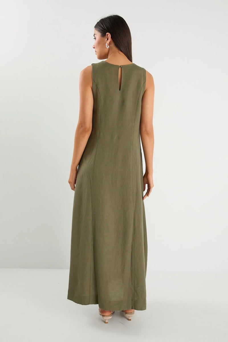 Model wearing Re:Union The Label Easygoing Khaki Linen Blend Sleeveless Crew Neck Midi Dress with relaxed fit, midi length, and side pockets, styled with sandals by the ocean