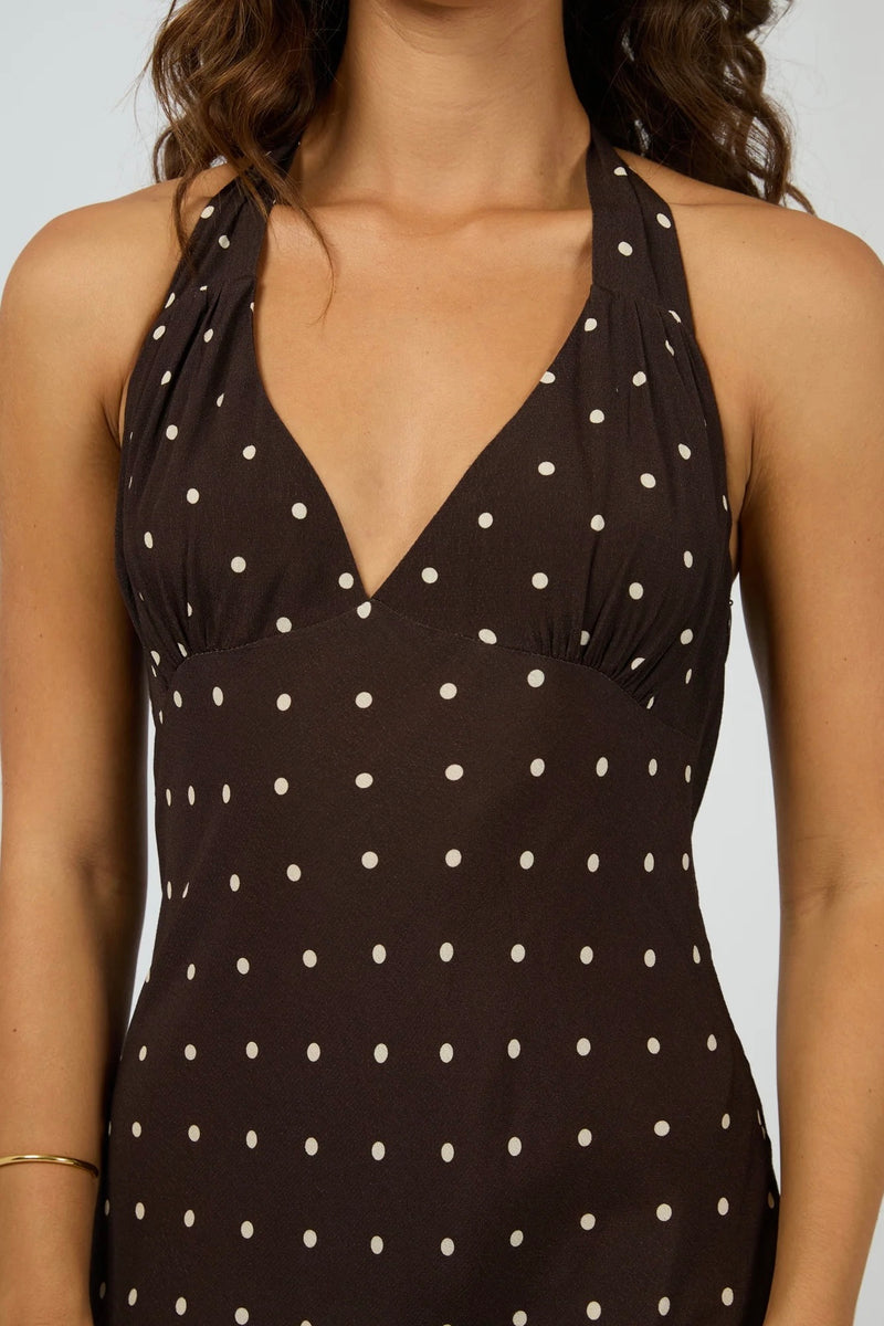 Model wearing All About Eve Emelia Maxi Dress in brown with ivory polka dots, halter neckline, sleeveless design, and flowy maxi length.