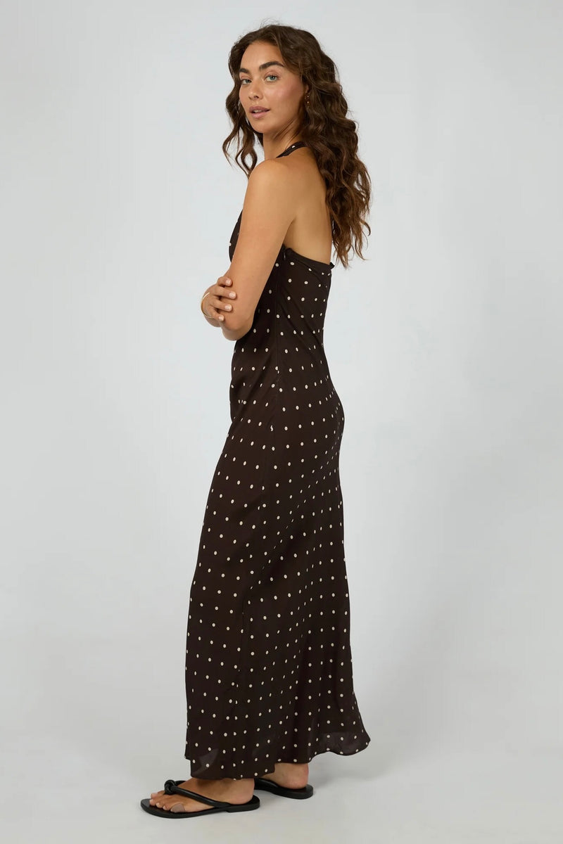 Model wearing All About Eve Emelia Maxi Dress in brown with ivory polka dots, halter neckline, sleeveless design, and flowy maxi length.