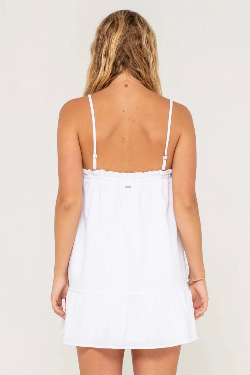Model wearing Rusty Mary Weather Mini Dress in white with spaghetti straps and frill hem against plain background.