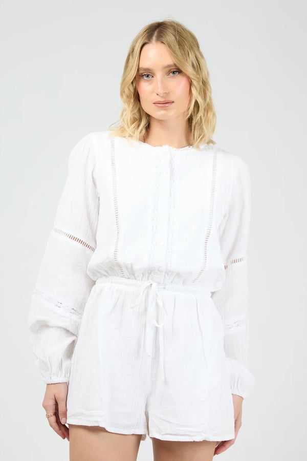 Model wearing the All About Eve Dusty Playsuit in white, featuring long sleeves, lace detailing, and a drawstring waist.
